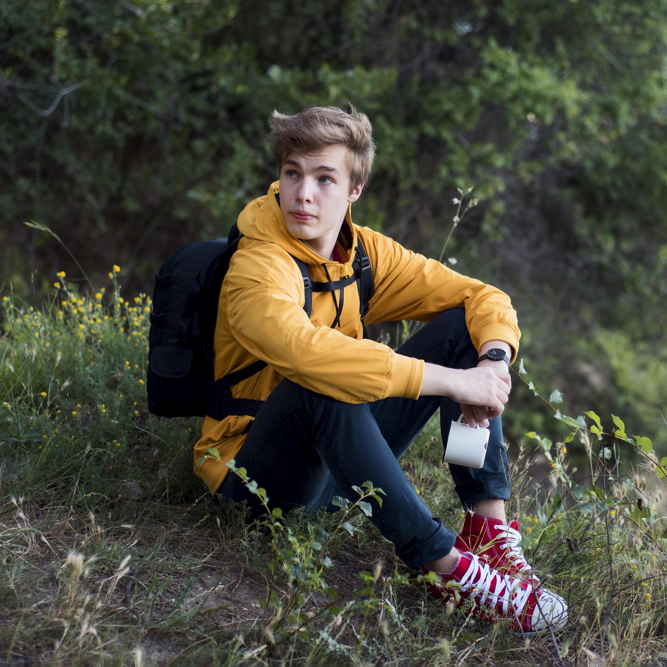 full-shot-teen-with-backpack-sitting-ground-forest (1)